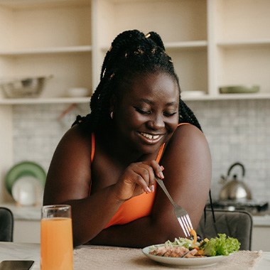 Woman smiling while eating healthy meal at home