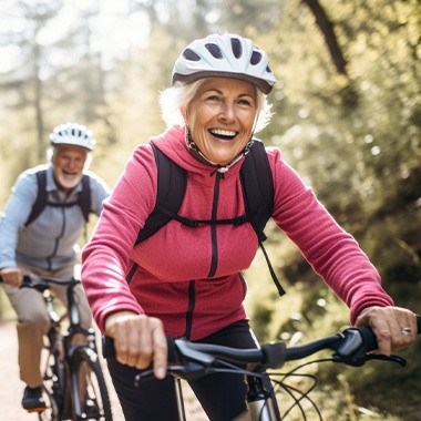 Couple smiling while riding their bikes on nature trail