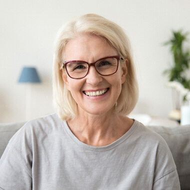 woman with glasses sitting on couch and smiling