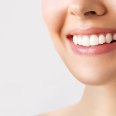 Nose-to-neck view of woman with white teeth smiling